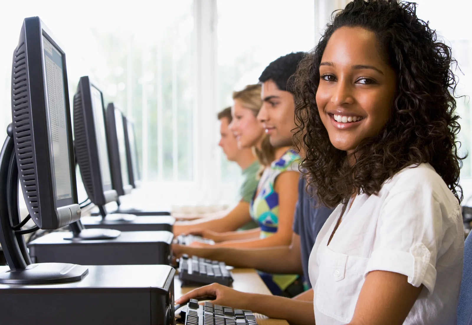Students working side by side at computers in a school lab.